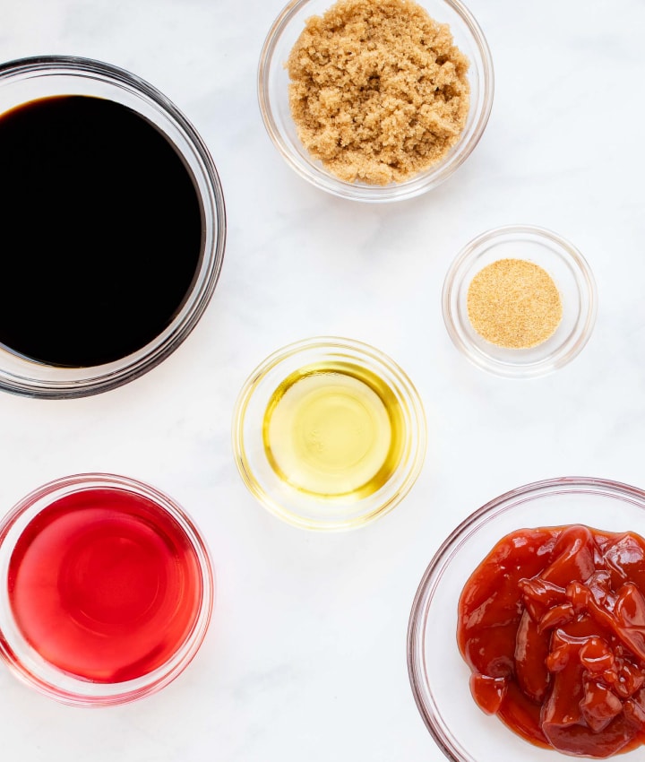 overhead shot of bowls with red wine vinegar, woy sauce, brown sugar, oil, garlic salt, and ketchup