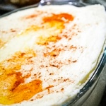 Glass dish with mashed potatoes topped with butter and paprika