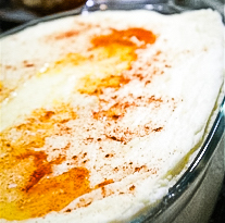 Glass dish with mashed potatoes topped with butter and paprika