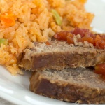 Mexican style rice on a plate with two slices of roast beef and diced tomatoes