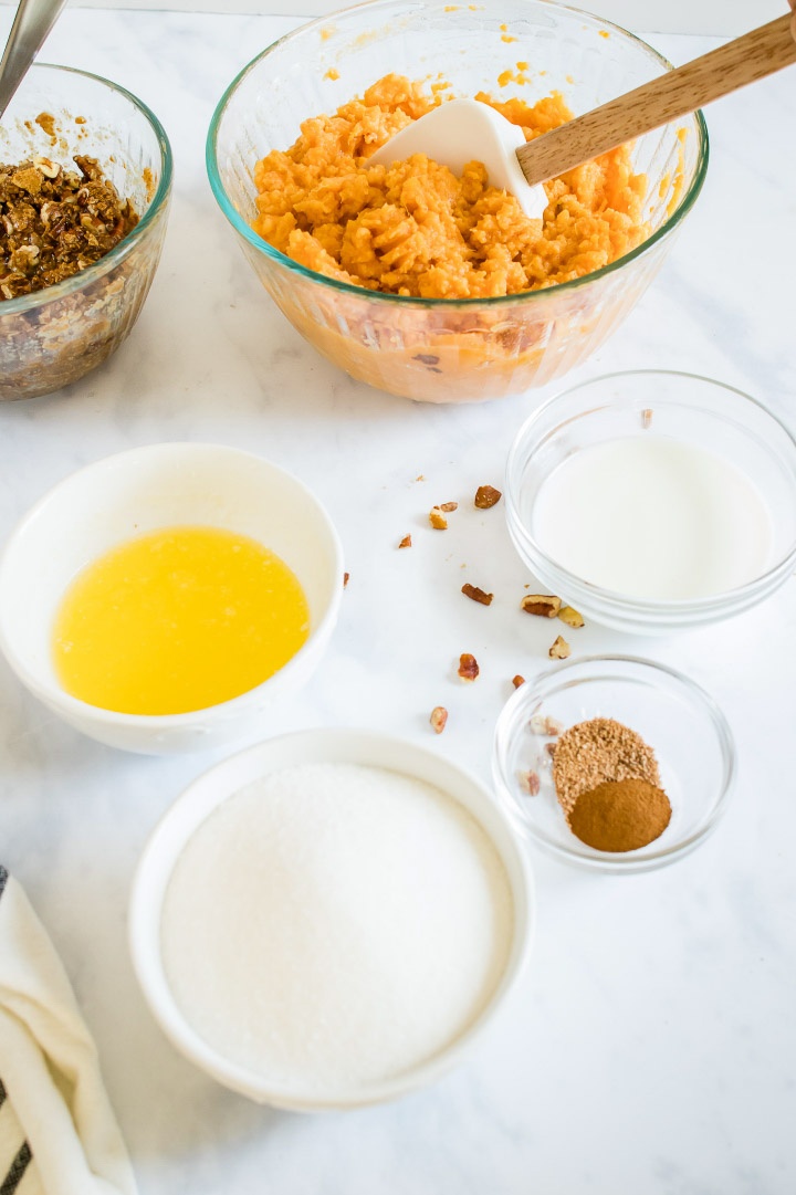 Ingredients for sweet potato casserole: streusel topping, mashed sweet potatoes, melted butter, sugar, nutmeg, cinnamon, and milk