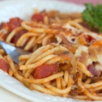 Baked spaghetti on white plate with a fork