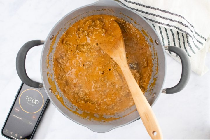 Overhead view of unbaked penne pasta bake topped with shredded cheese in a glass pan