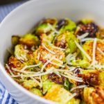 White bowl with roasted Brussels sproups garnished with parmesan cheese