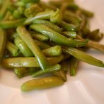 Slow simmered green beans on a white dish.