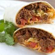 A beef burrito cut in half on a white plate