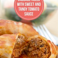Closeup of cabbage rolls in a tomato sauce on a white plate with a fork. Bowl of salad in the background. Text is Cabbage Rolls in Sweet & Tangy Tomato Sauce - Add Salt & Serve logo