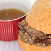 A roast been sandwich with a small bowl of au jus.