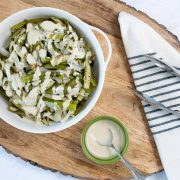 A bowl of roasted okra and onions beside a small cup of horseradish sauce.