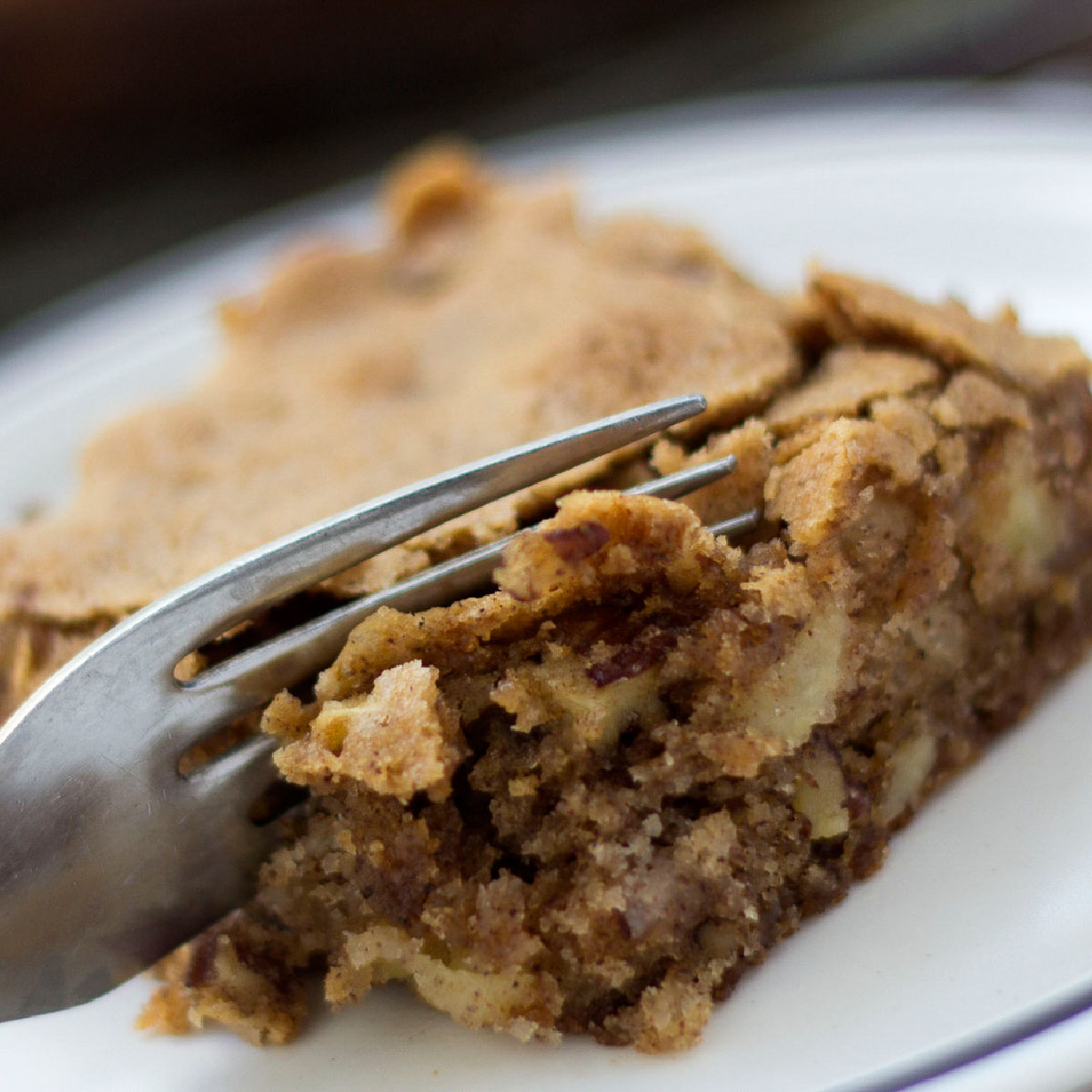 A fork cutting into an Apple Walnut Bar that is crisp on the top and moist on the inside.
