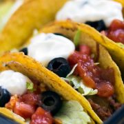 Hard-shell tacos with beef, lettuce, olives, salsa, and sour cream