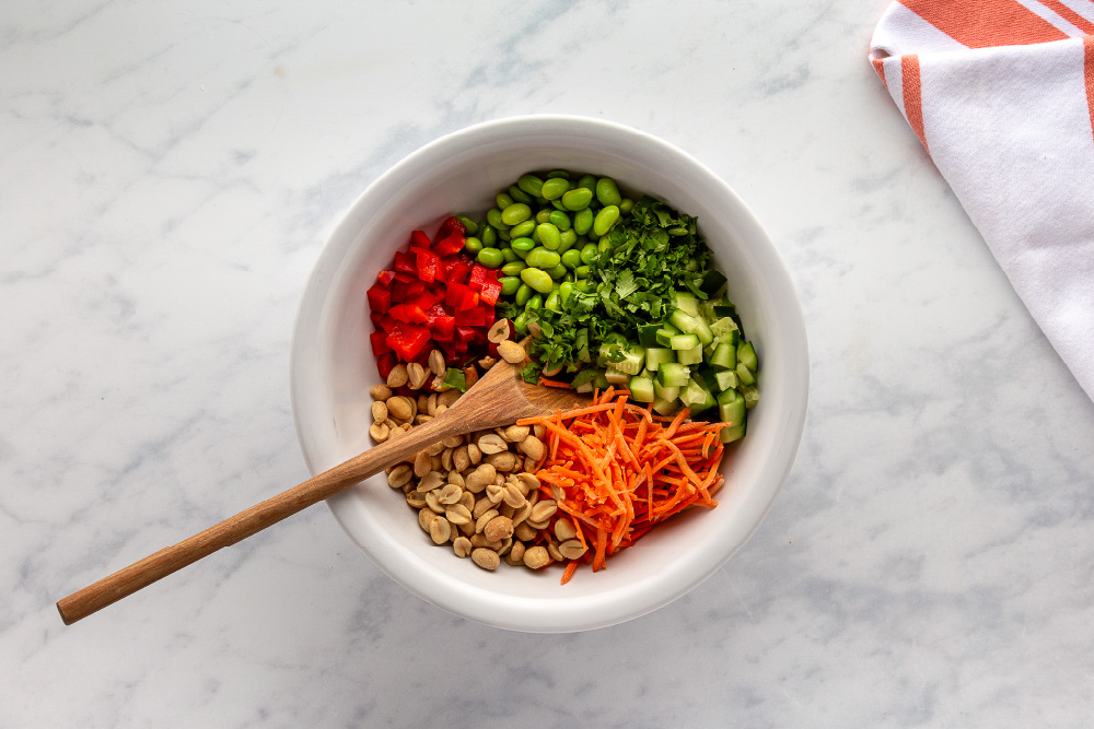 Carrots, Red Bell Pepper peanuts, edamame, and cilantro in a bowl