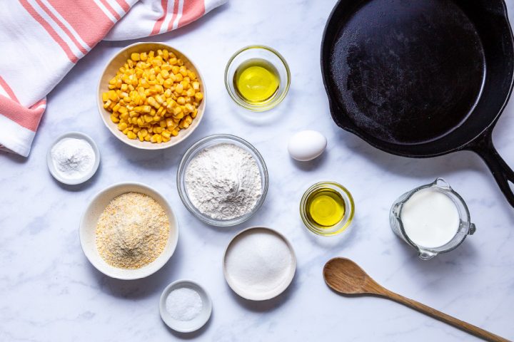cast iron skillet and ingredients for cornbread with corn kernels