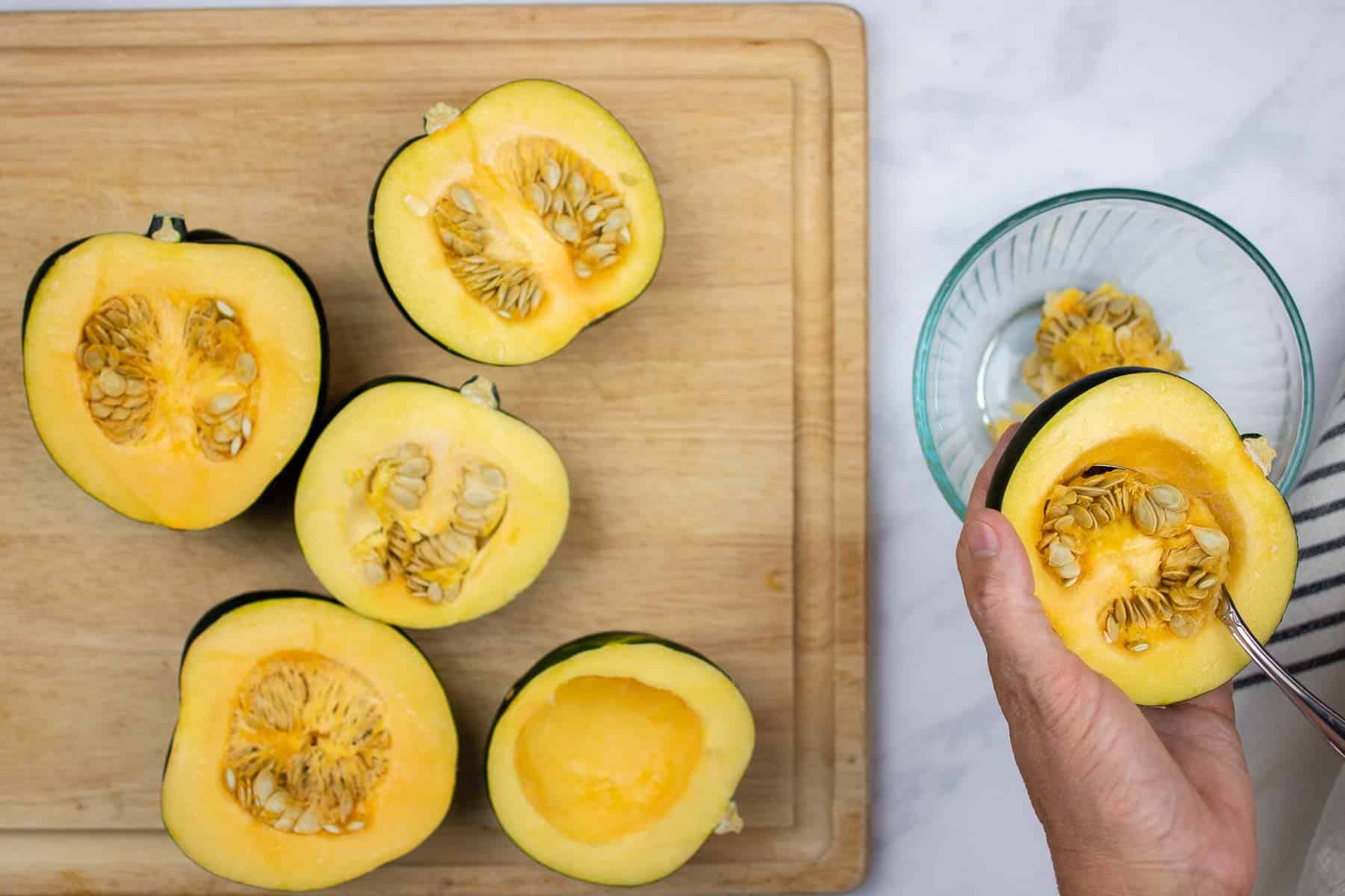 Cleaning acorn squash halves.