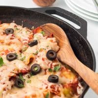 Mexican Ravioli in a cast iron skillet with a wooden spoon.