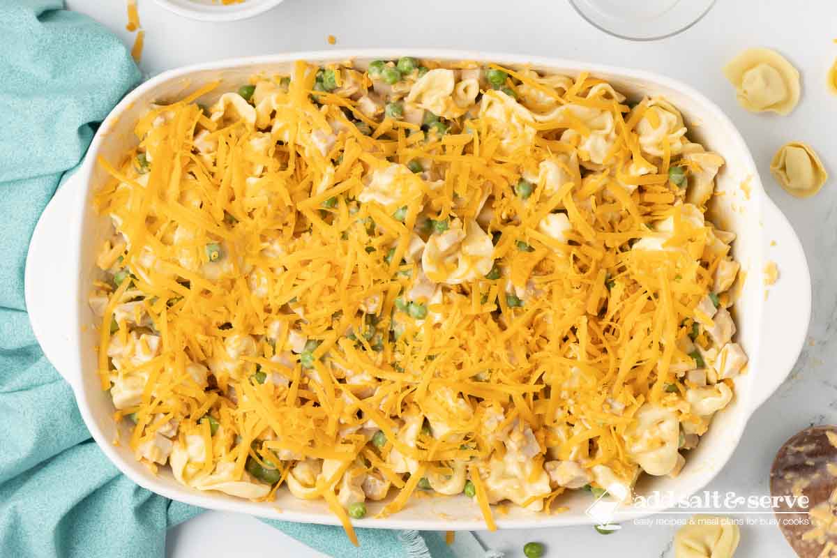 Tortellini, turkey, and peas in a cheesy casserole before baking.