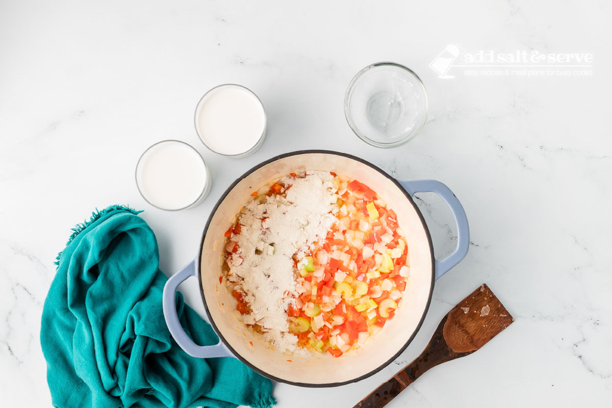 Enamel Dutch oven with chopped onion, red bell pepper, celery, and minced garlic sautéed in butter and flour added to thicken.