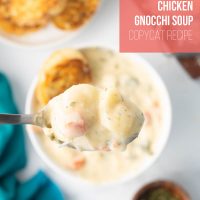 A spoonful of Copycat Olive Garden Chicken Gnocchi soup held over a bowl full of soup with toasted garlic bread in the bowl.