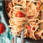 Cooked Stovetop Zucchini Linguine wrapped on tongs held over the skillet.