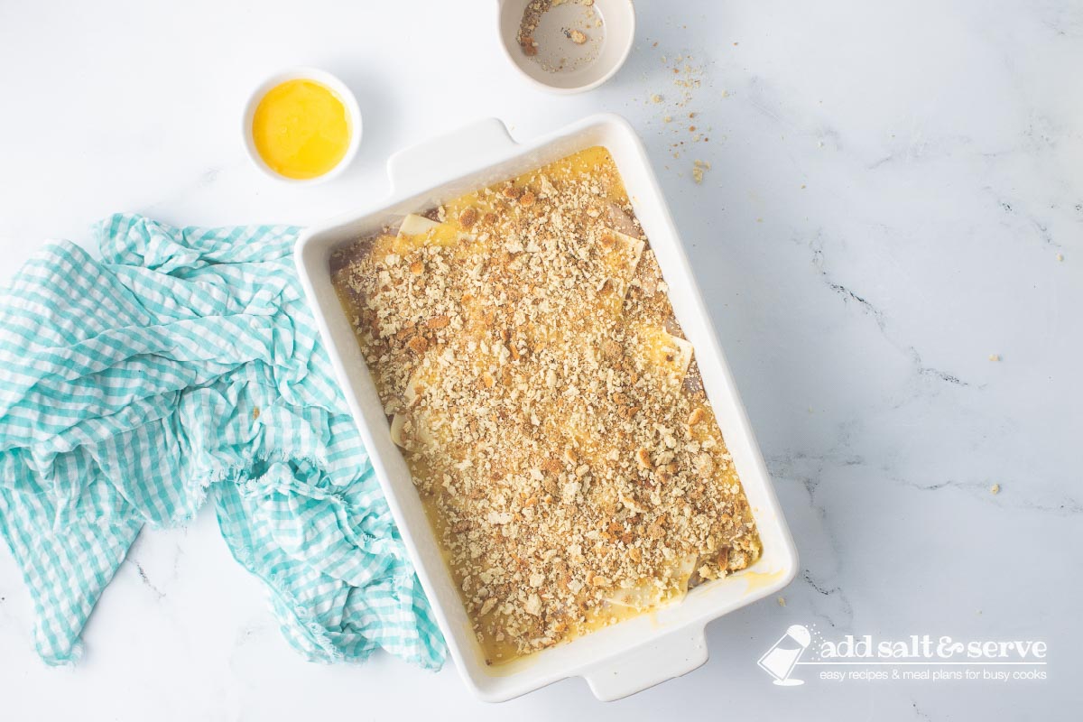 Casserole dish of Swiss chicken with white wine and stuffing before adding melted butter to the top of the stuffing.