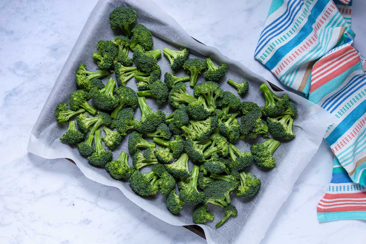 Broccoli florets on a baking sheet lined with parchment paper