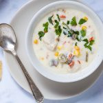 Bowl of Southwest Chicken Corn Chowder garnished with cilantro on a saucer with a spoon.