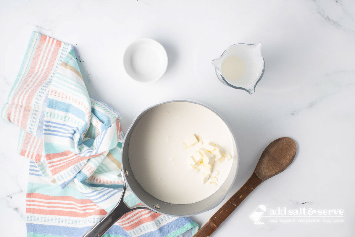 A saucepan with cream and chopped butter.