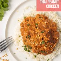 Plated slow cooker Thai Peanut Chicken over rice garnished with chopped peanuts and cilantro.