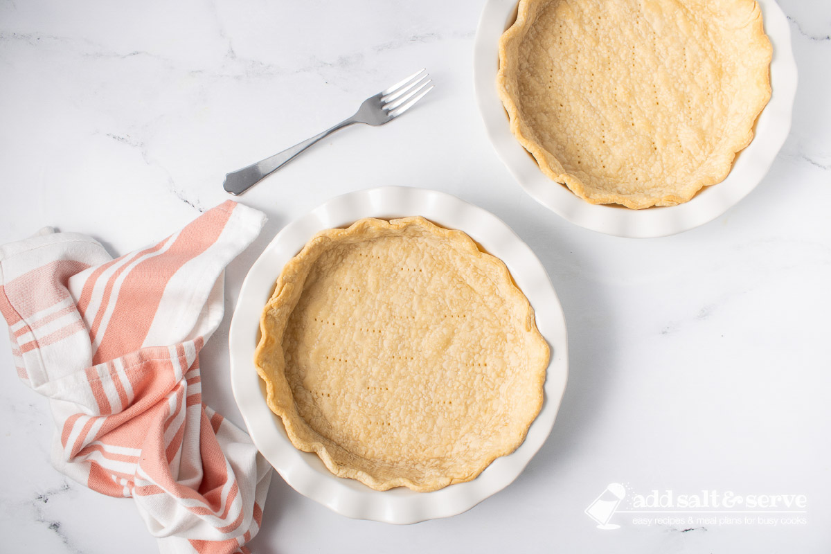 Overhead view of two empty baked pie crusts in white pie plates.