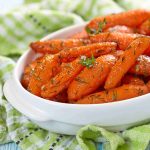 Glazed carrots garnished with parsley in a serving bowl.