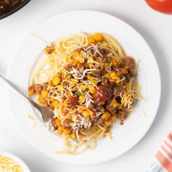 Plate of Mexican Spaghetti topped with shredded cheese.