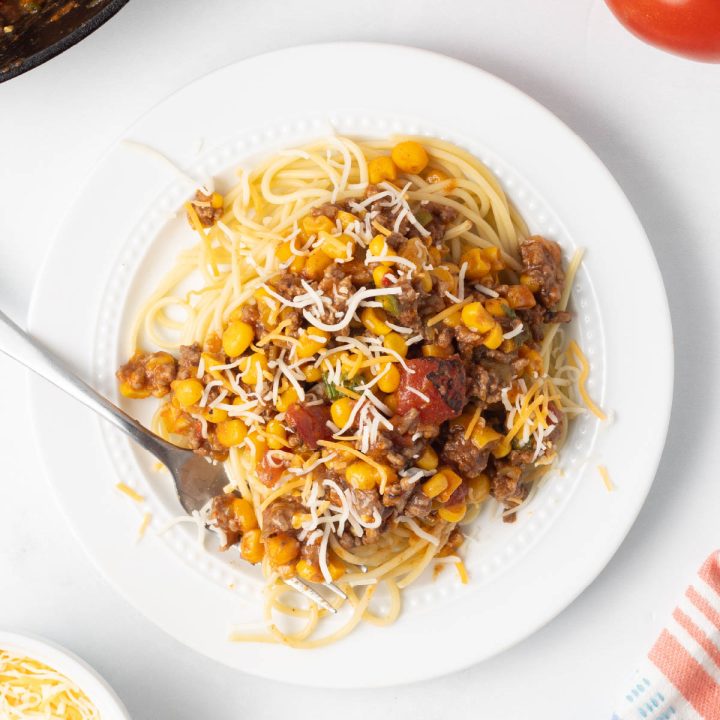 Plate of Mexican Spaghetti topped with shredded cheese.