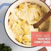 Dutch oven of creamy summer squash and cheese ravioli in a cheese sauce with text Creamy Cheese Ravioli with Summer Squash.