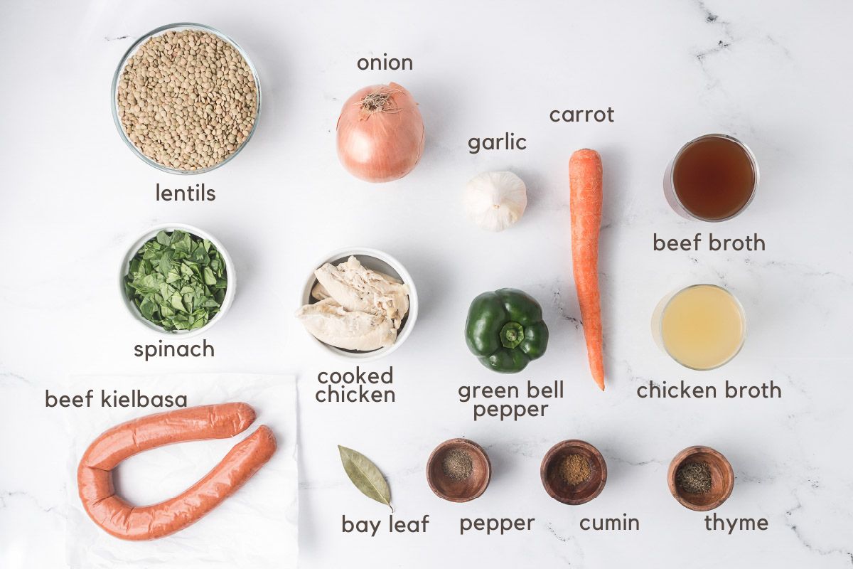 Ingredients for Crockpot Lentil Soup: lentils, carrot, onion, green pepper, kielbasa, bay leaf, chicken, garlic, thyme, pepper, cumin, beef broth, chicken broth, and spinach.