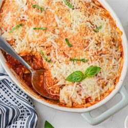 Casserole dish of baked frozen ravioli with a serving removed.