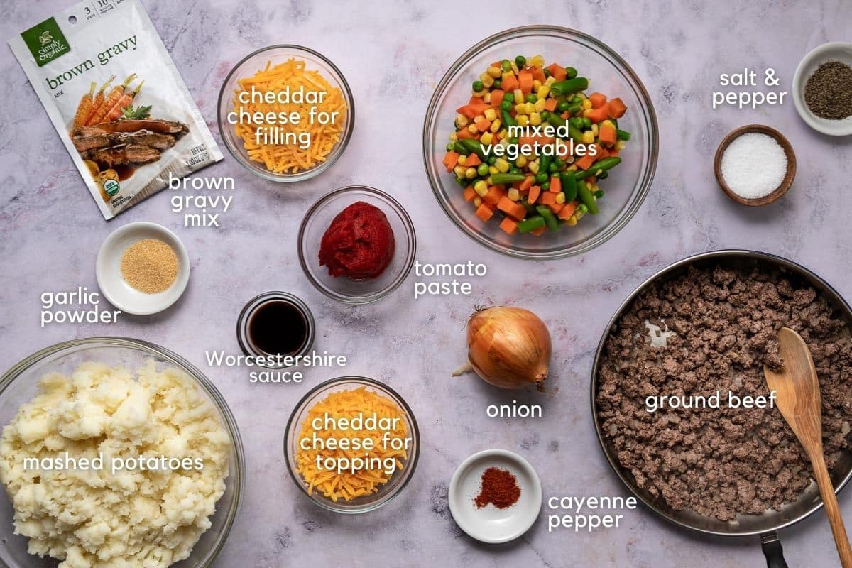 Ingredients for SHepherd's Pie: ground beef, onion, cayenne pepper, tomato paste, cheddar cheese, Worcestershire sauce, garlic powder, brown gravy mix, mashed potatoes, salt, and pepper.