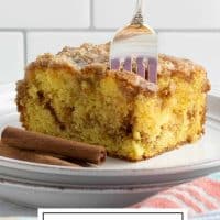Slice of Honey Bun Cake on a plate showing the cinnamon swirl in the middle and vanilla glaze on top with a fork stuck in the top of the cake and text Honey Bun Cake with box cake mix.