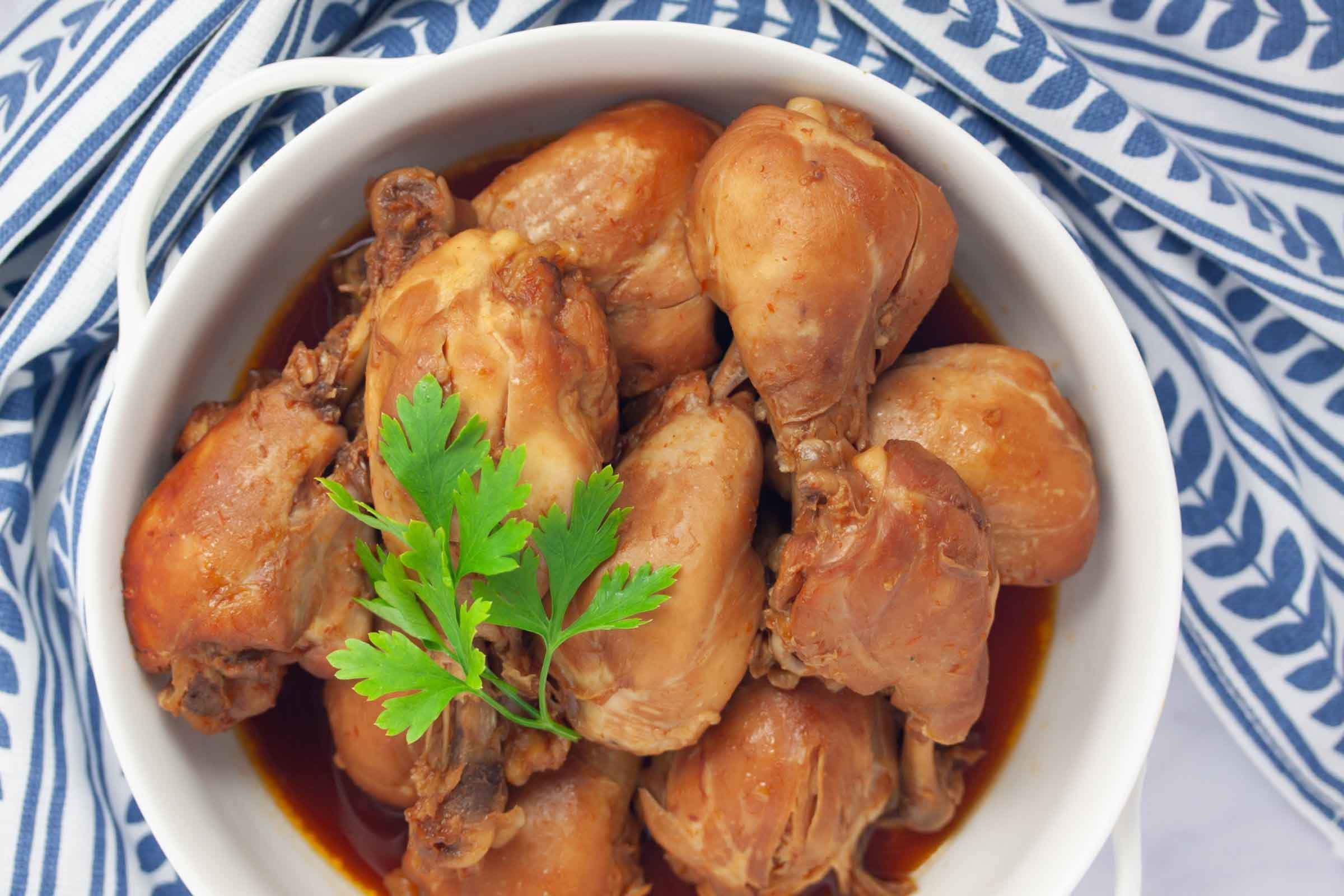 Cooked chicken legs with the meat falling off of the bones in a serving dish.