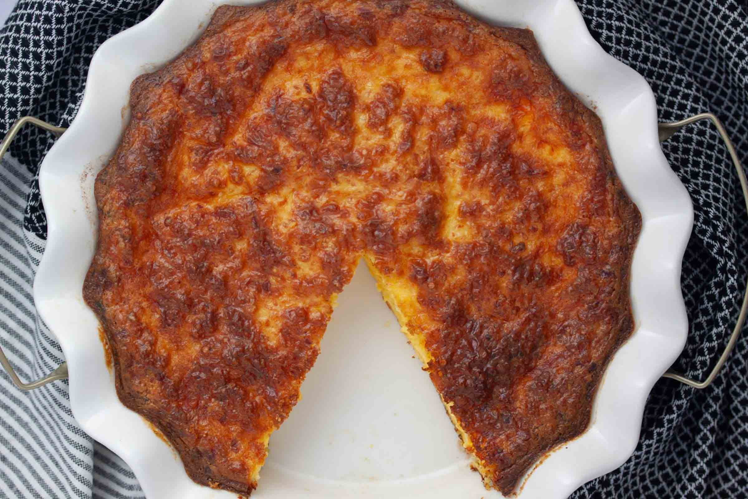 Overhead view of a slice of crustless quiche with one piece removed.
