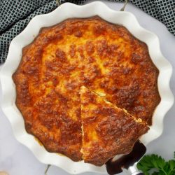 Overhead view of a slice of crustless quiche being lifted out of a pie plate.