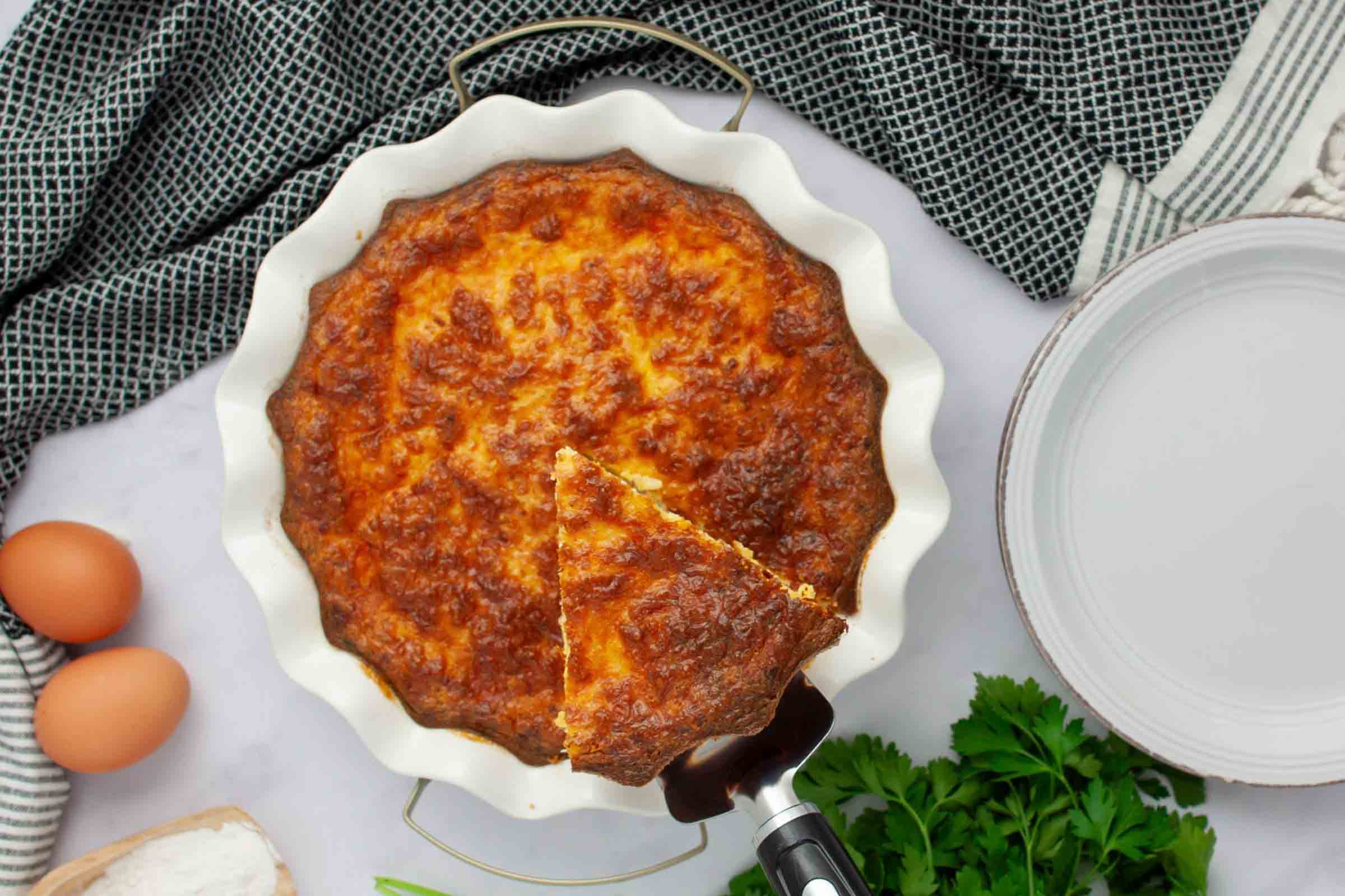 Overhead view of a slice of crustless quiche being lifted out of a pie plate.