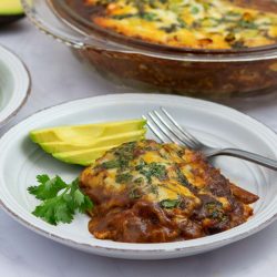 A plate with chicken enchilada bake garnished with sliced avocado.