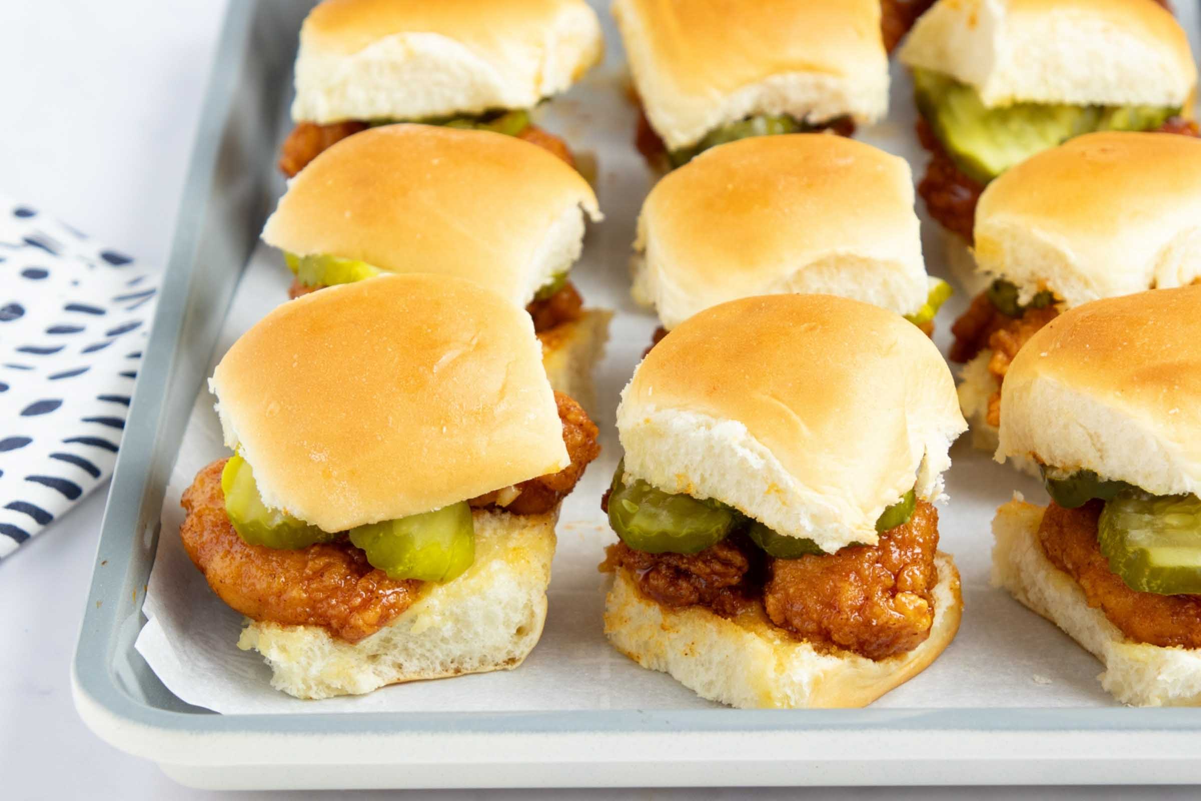 Hot honey chicken sliders with pickles on a baking sheet.