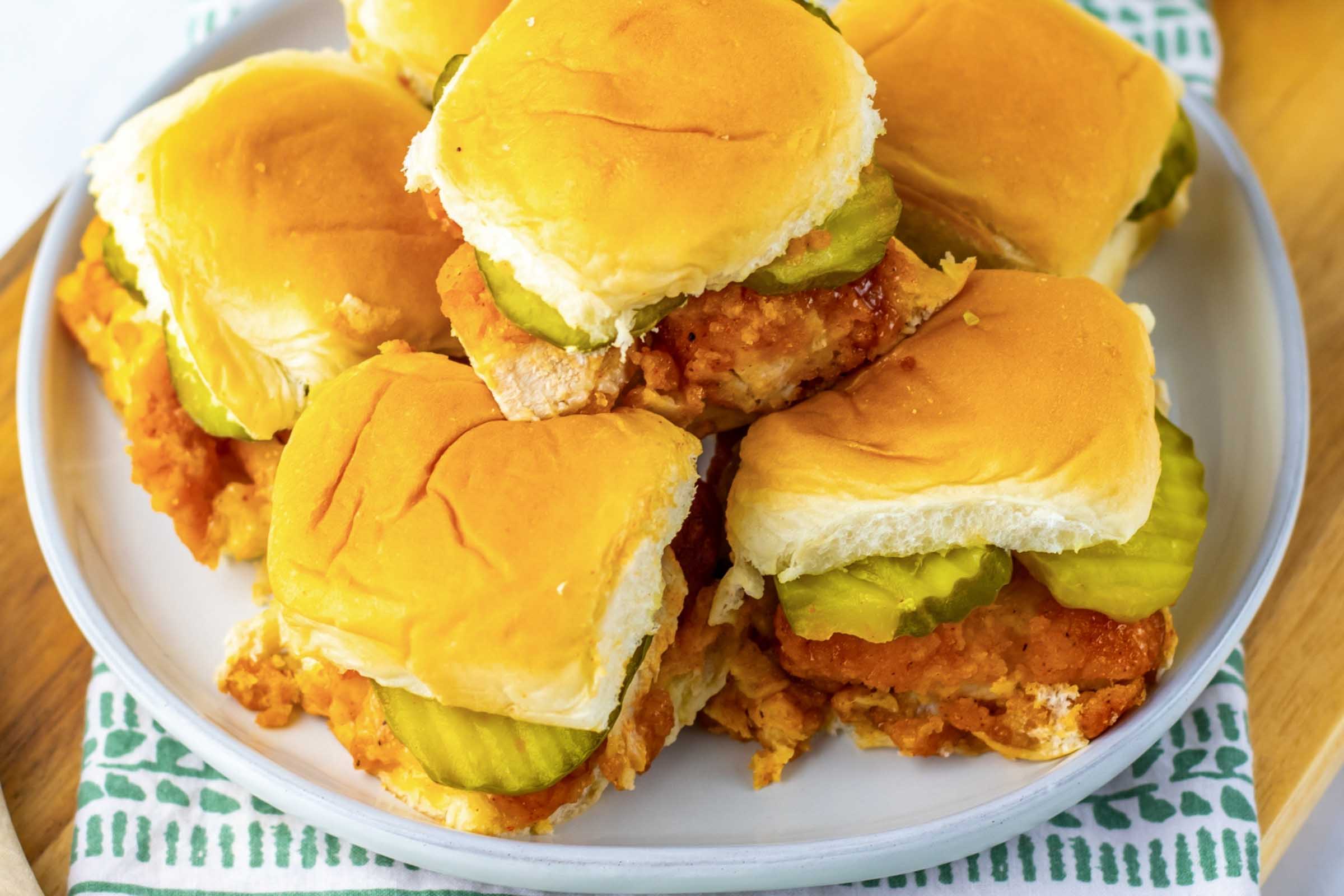 A pile of hot honey chicken sliders on a plate.