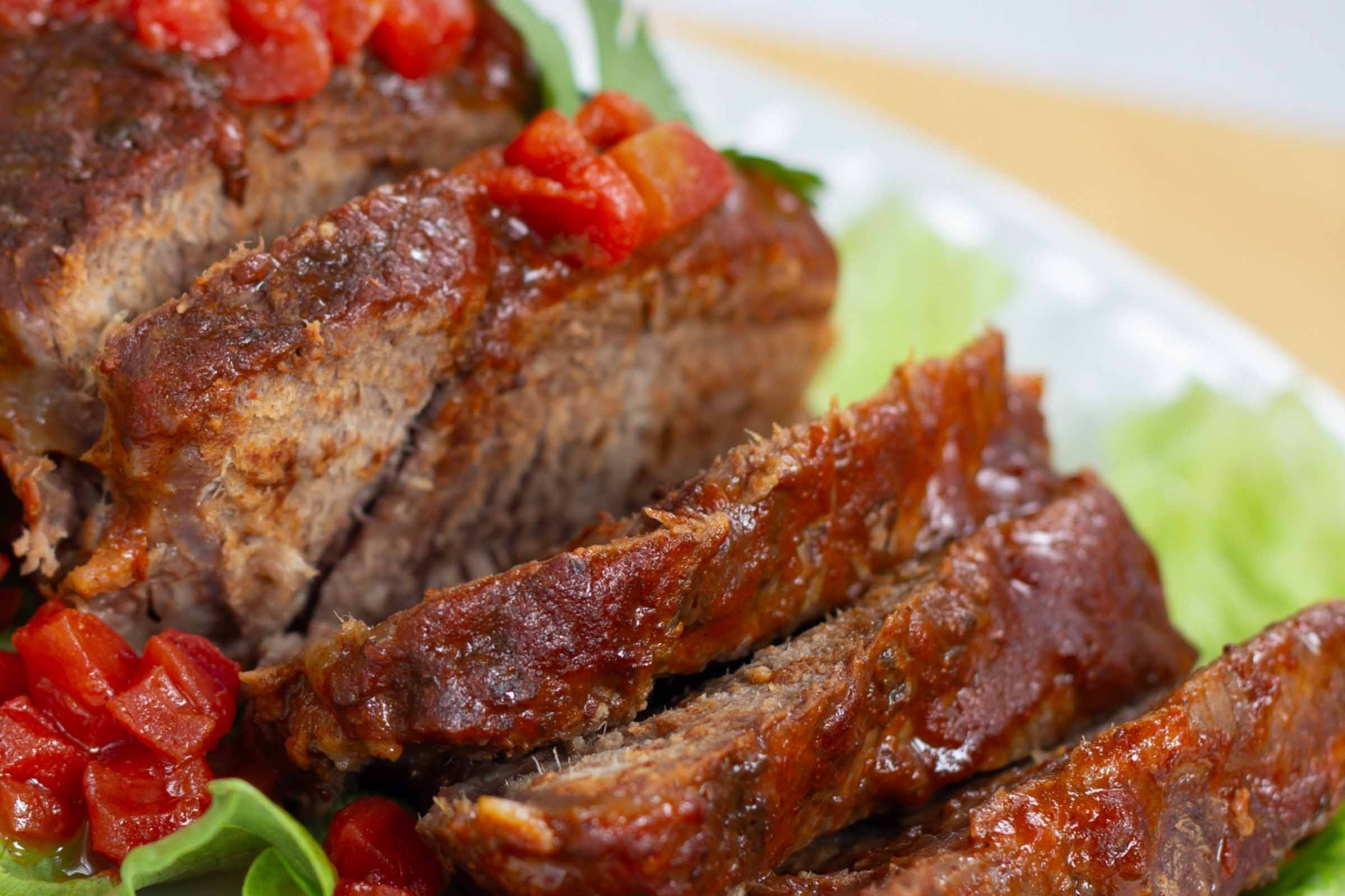 Mexican Style Pot Roast Sliced pot roast with diced tomatoes on top and a red sauce.