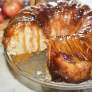 Apple upside down bundt cake with a slice removed and caramel sauce dripping down the sides.