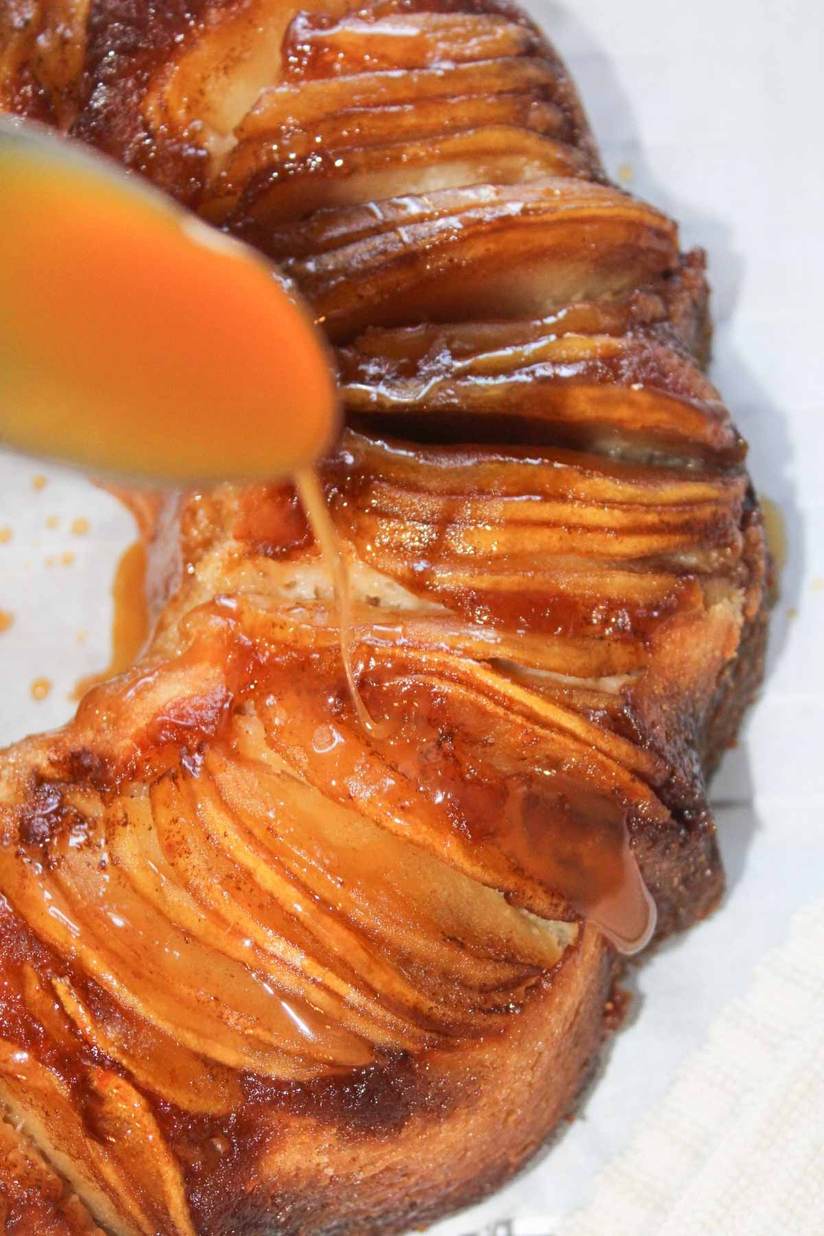 Drizzling caramel sauce from a spoon over apple upside down bundt cake.