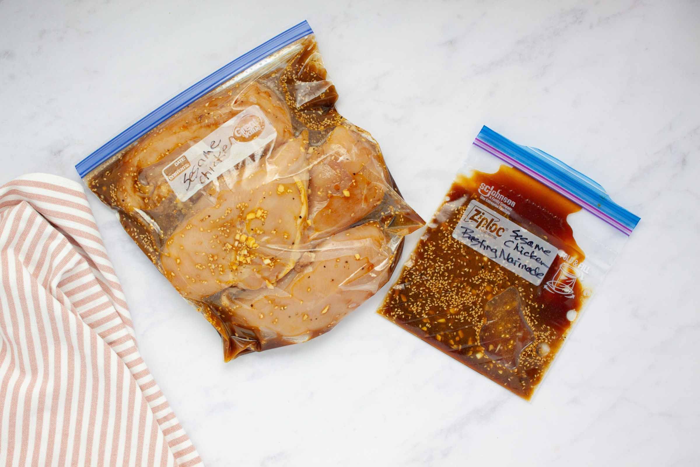 Two freezer bags, one with chicken breasts marinating in sesame marinade and the other with extra marinade for basting.