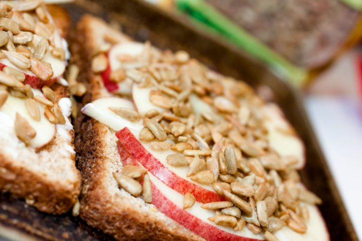 toast spread with mayo, apple slices, and sunflower seeds and text Add Salt & Serve