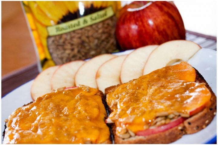 Open-faced Apple Cheddar Melt Sandwich with bread, mayo, apple slices, sunflower seeds, and cheddar melted on top and text Apple Cheddar Melt: Add Salt & Serve